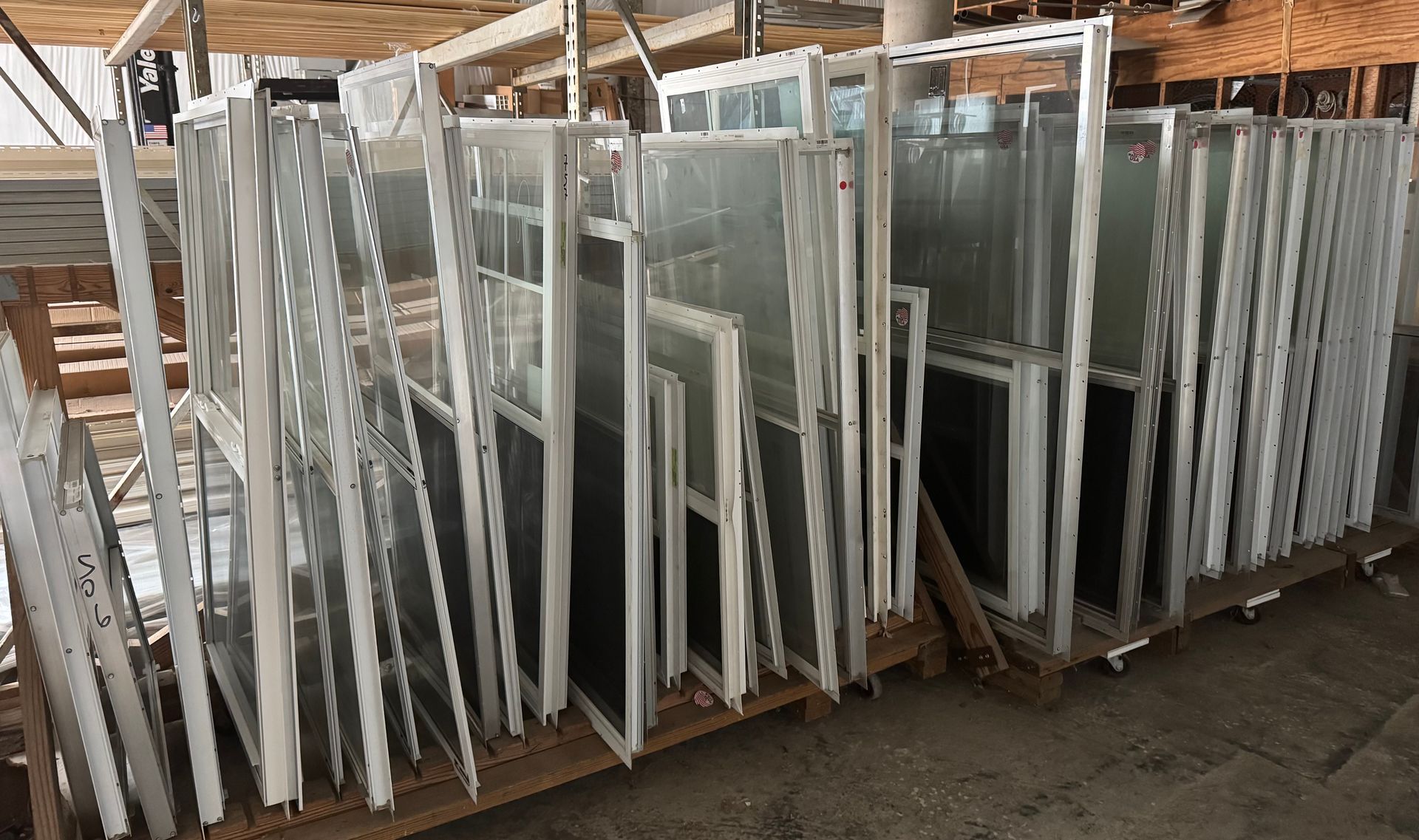 A bunch of windows are stacked on top of each other in a warehouse.