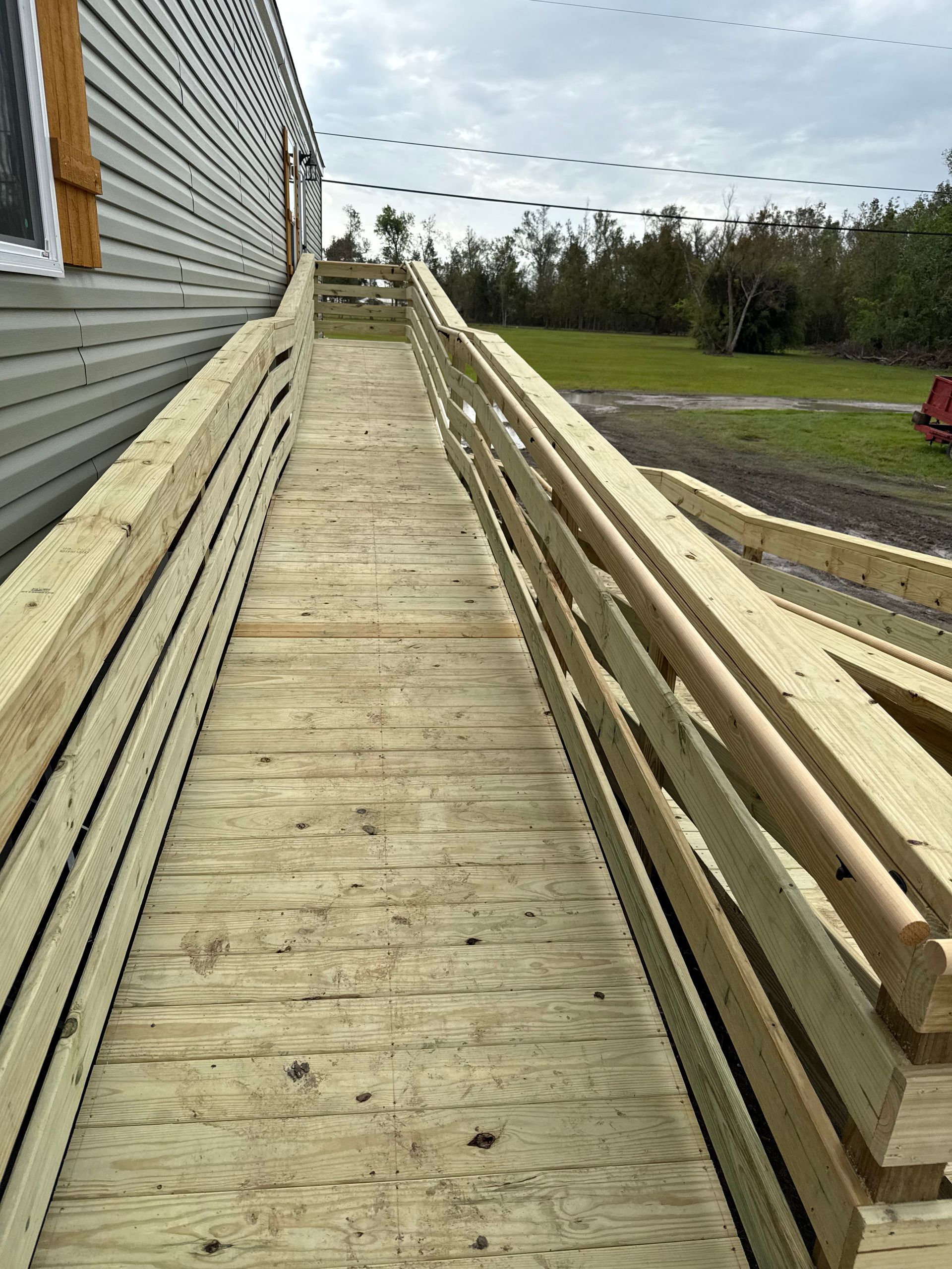 A wooden ramp leading to a house with a railing.