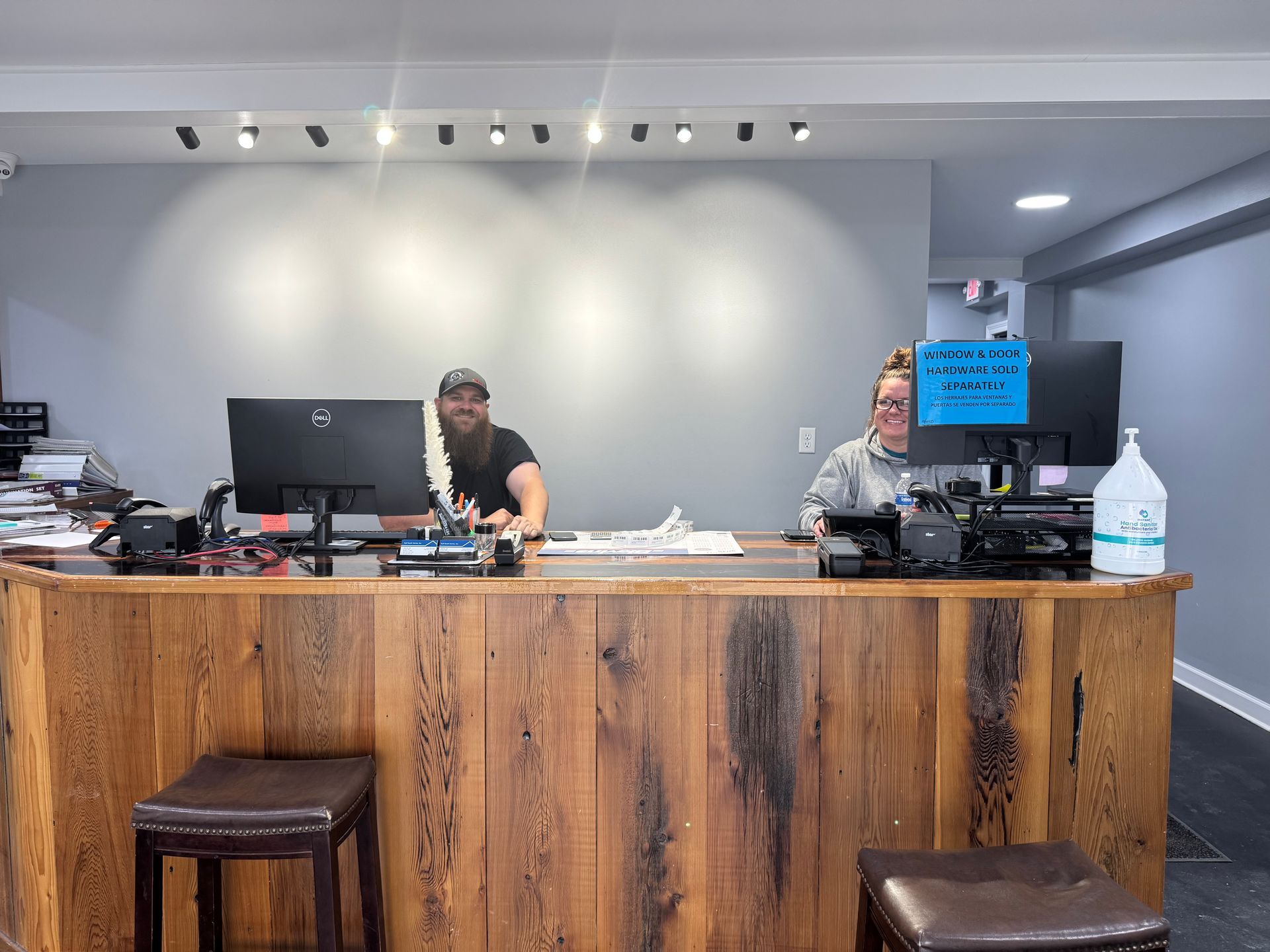 A man and a woman are standing behind a wooden counter.