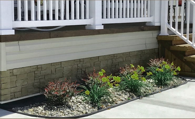 A planter with flowers in front of a house with stairs