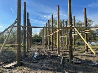 A wooden structure is being built in the middle of a dirt field.