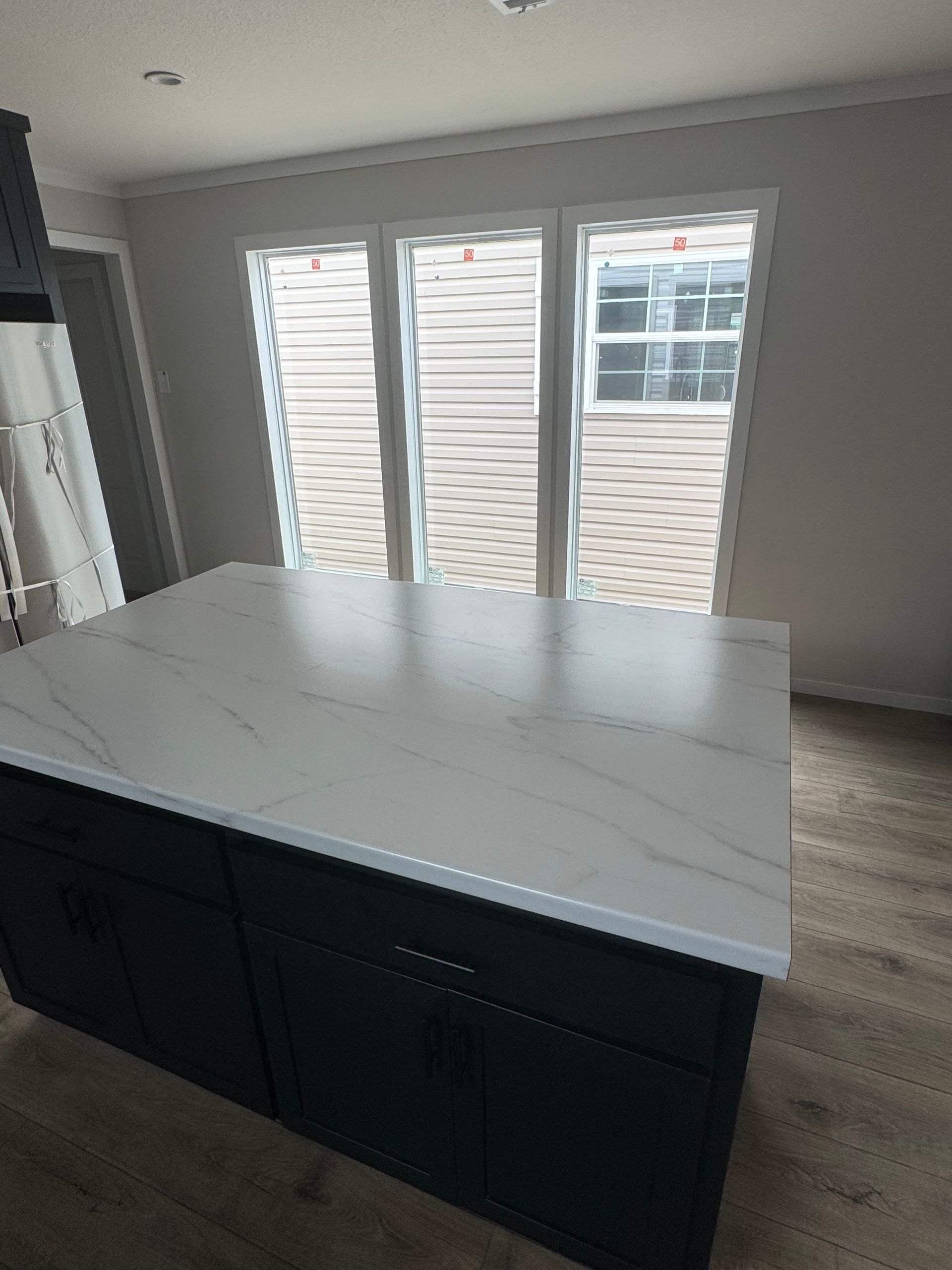 A kitchen with a large island and a white counter top.
