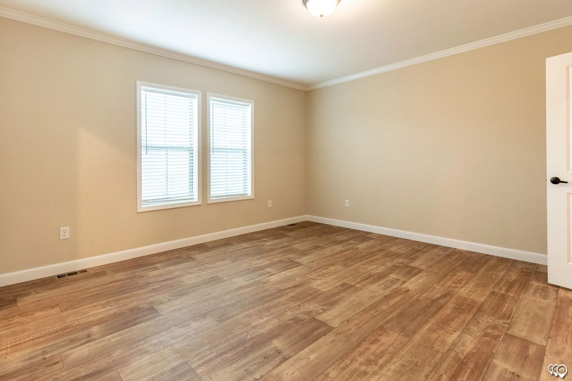 An empty room with hardwood floors and two windows.