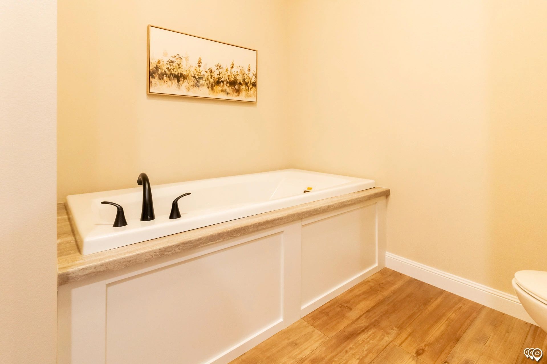 A bathroom with a bathtub and a painting on the wall.