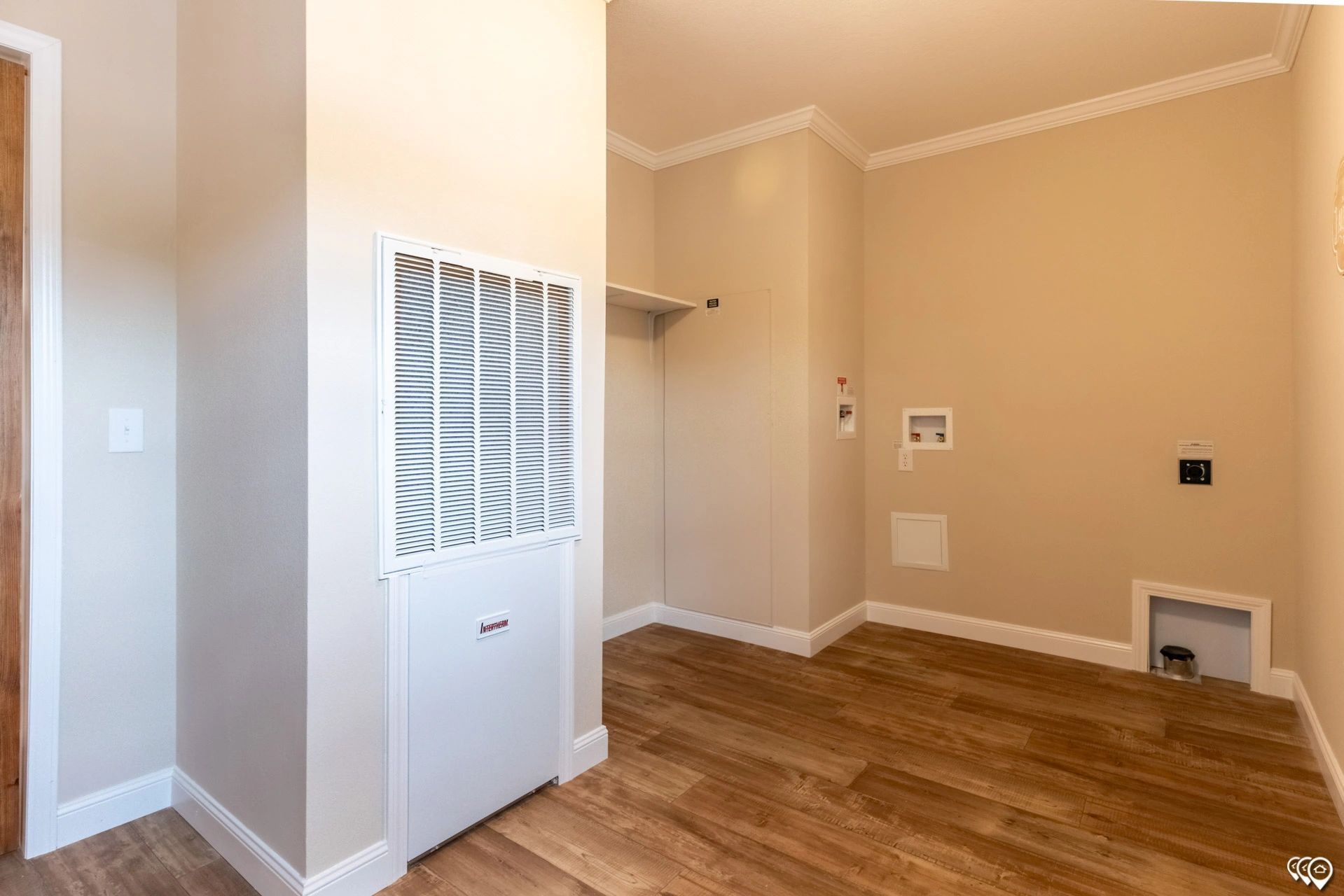 An empty laundry room with hardwood floors and a washer and dryer.