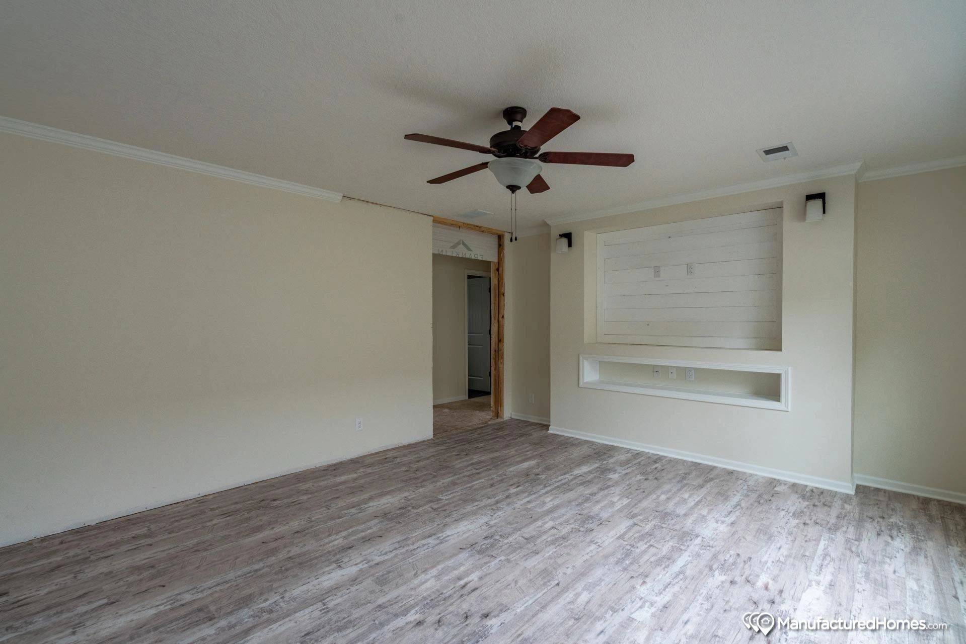 An empty living room with a ceiling fan and a fireplace.