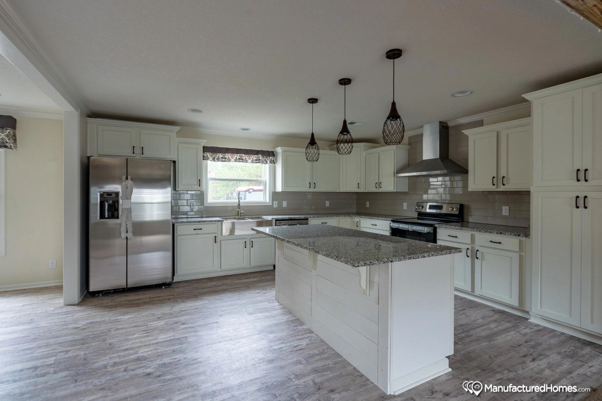 A kitchen with white cabinets , granite counter tops , stainless steel appliances and a large island.