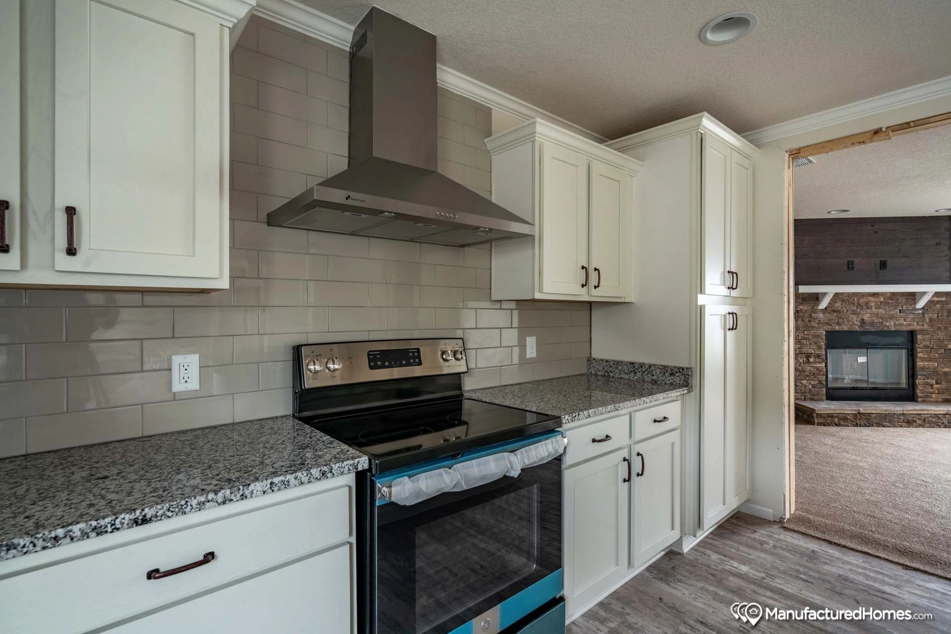 A kitchen with white cabinets , a stove , and a fireplace.