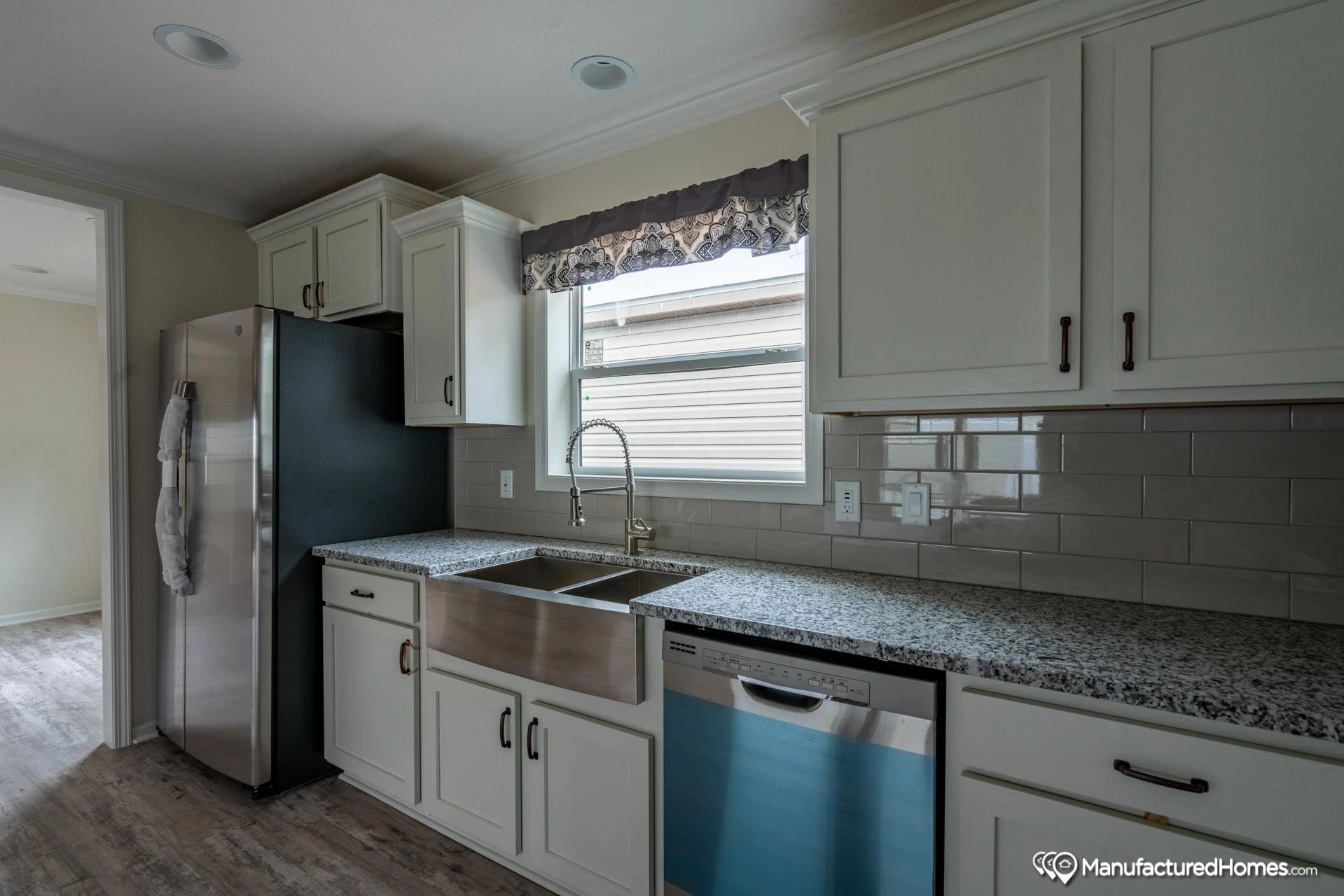 A kitchen with white cabinets , granite counter tops , stainless steel appliances and a sink.