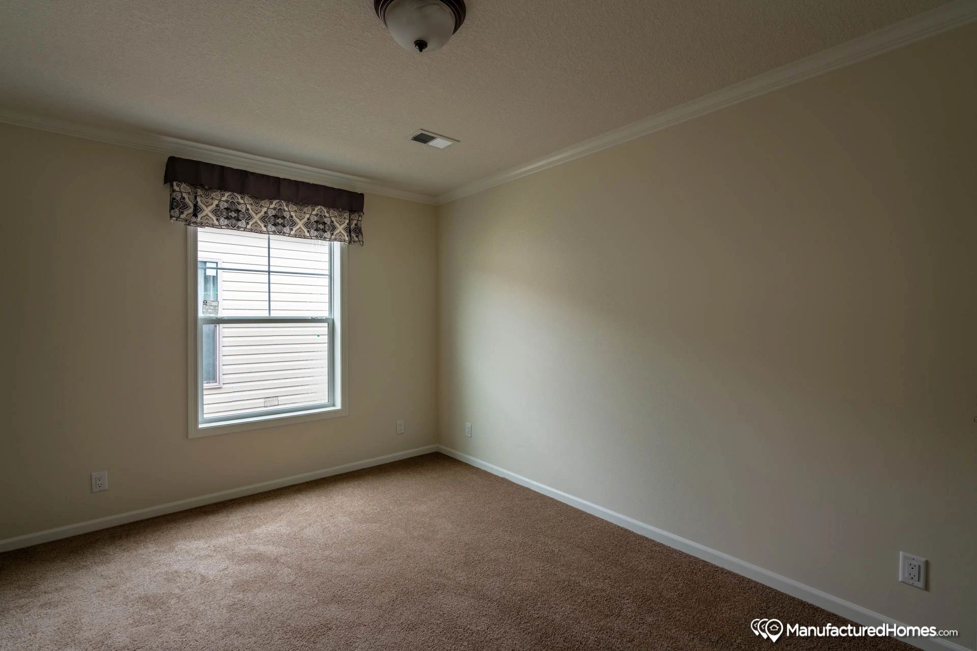 An empty bedroom with a window and carpet.