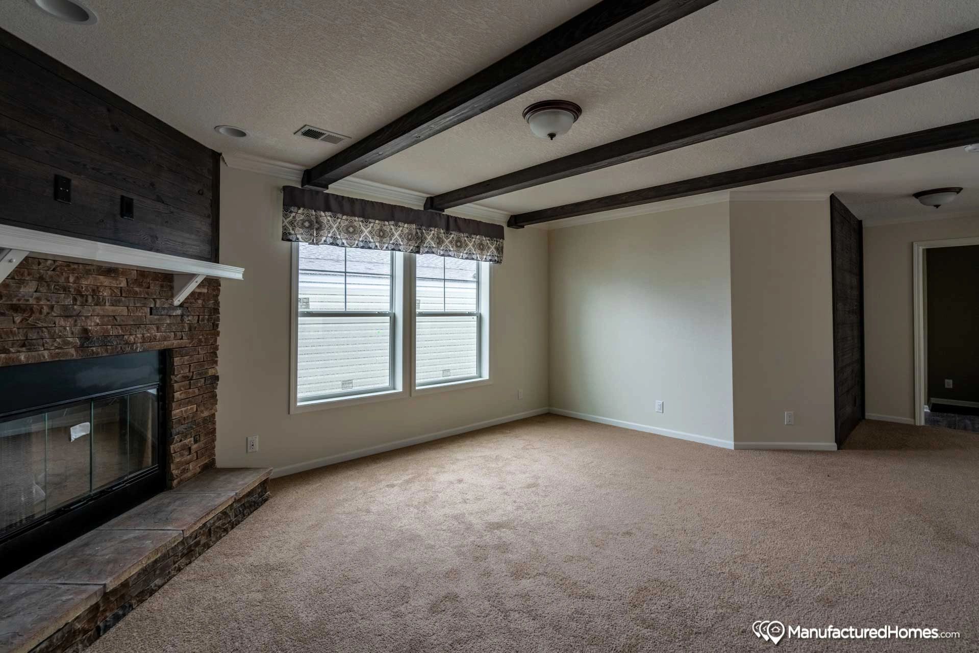 An empty living room with a fireplace and a lot of windows.
