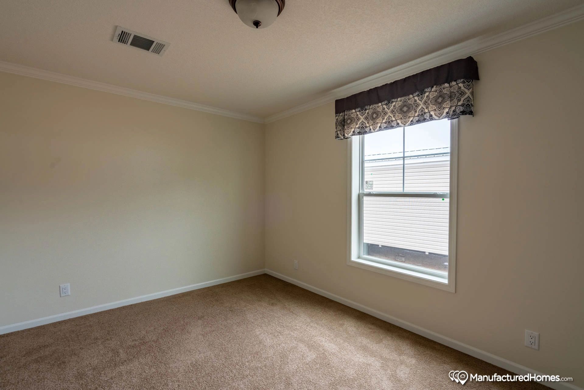 An empty bedroom with a window and carpet.