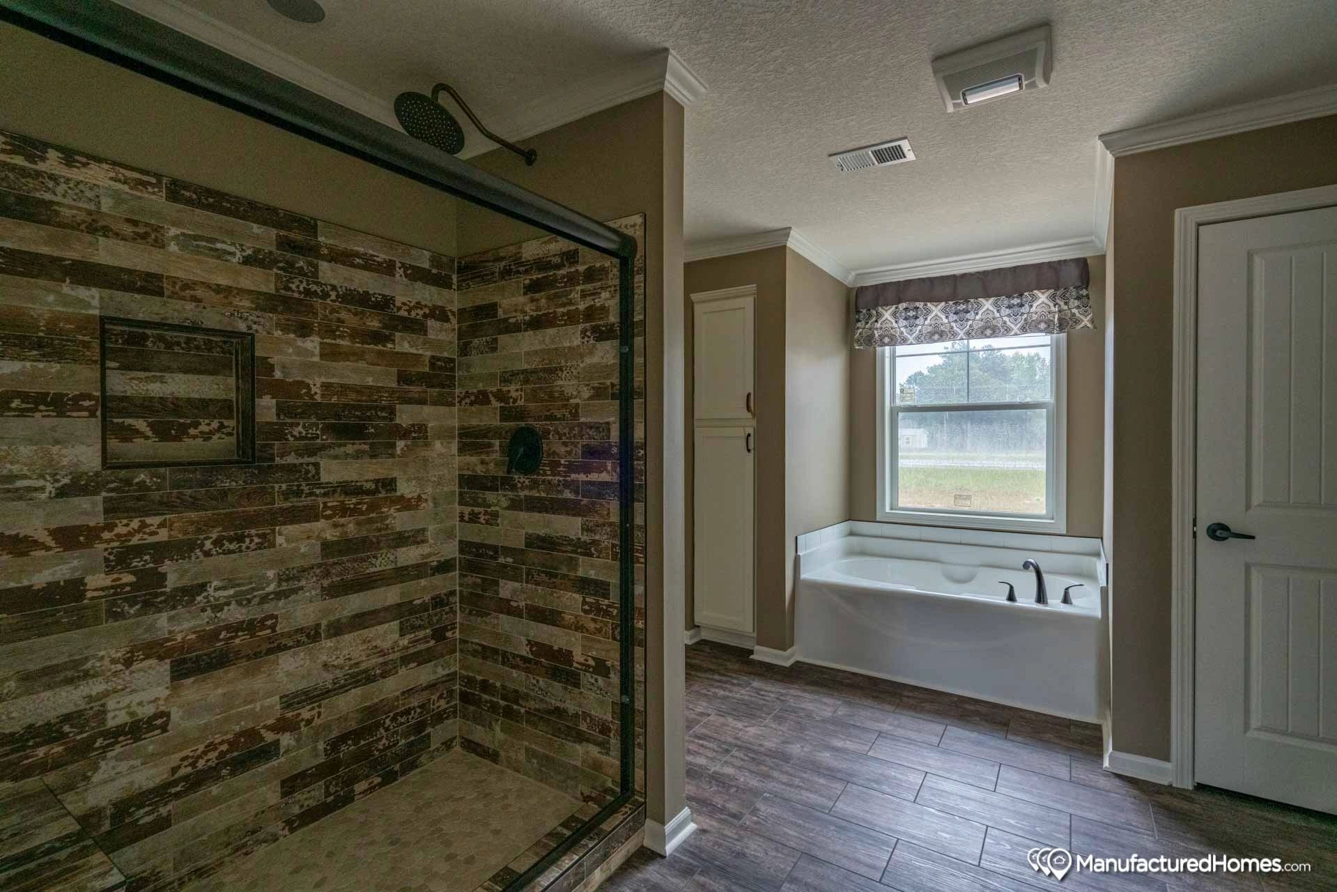 A bathroom with a walk in shower and a tub.
