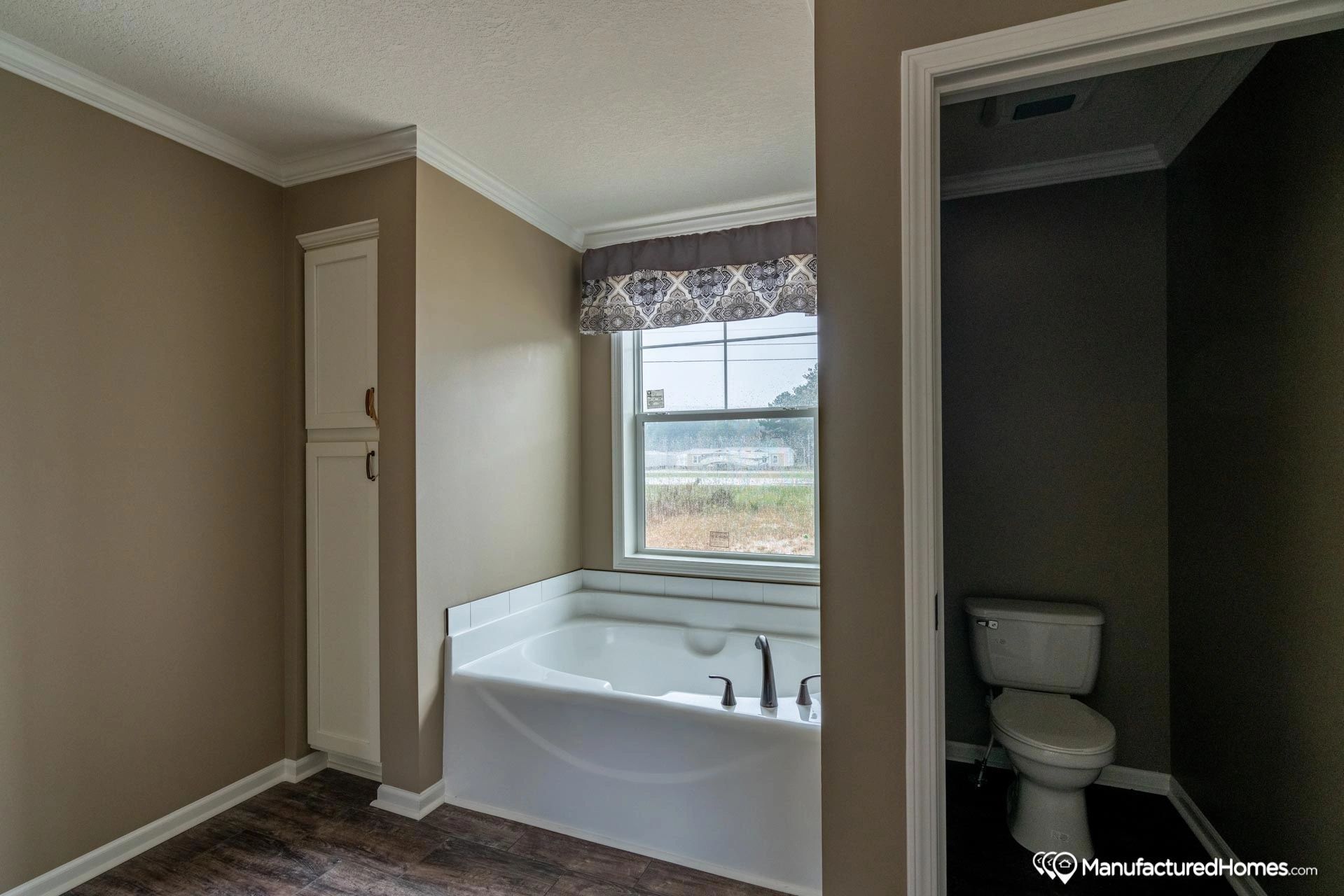 A bathroom with a tub , toilet and window.