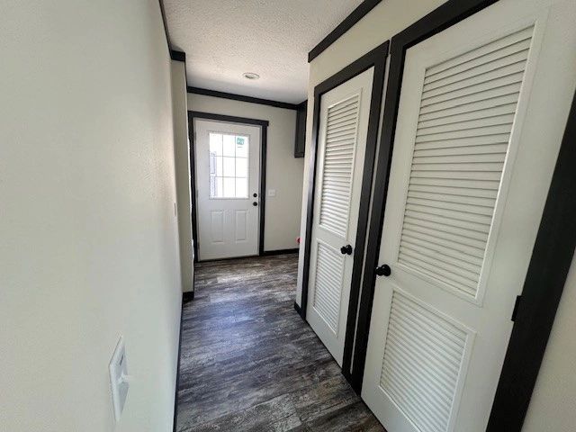 A hallway with a door and closets in a house.