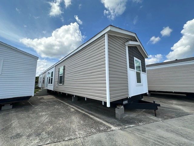A mobile home is parked in a parking lot next to a trailer.
