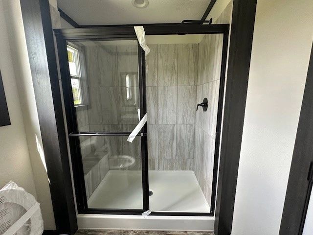 A bathroom with a sliding glass shower door and a toilet.