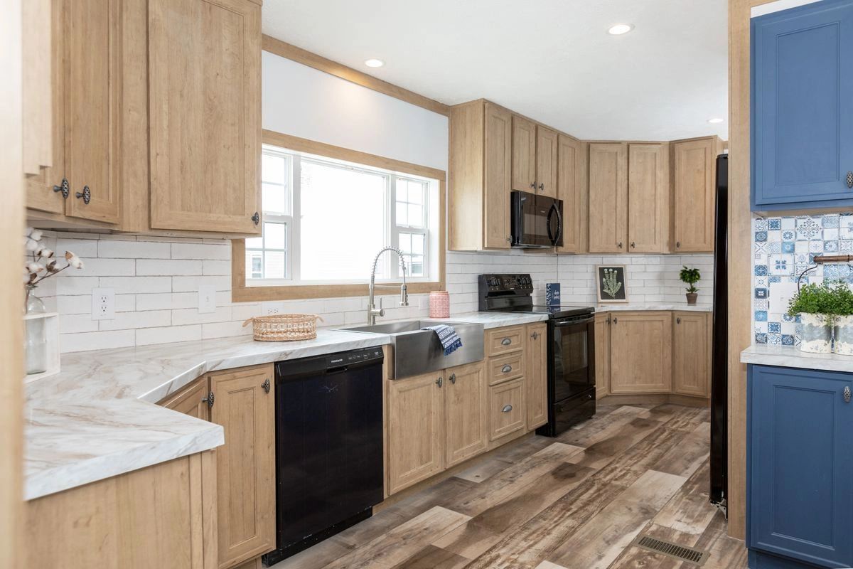 A kitchen with wooden cabinets , black appliances , a sink , and a window.