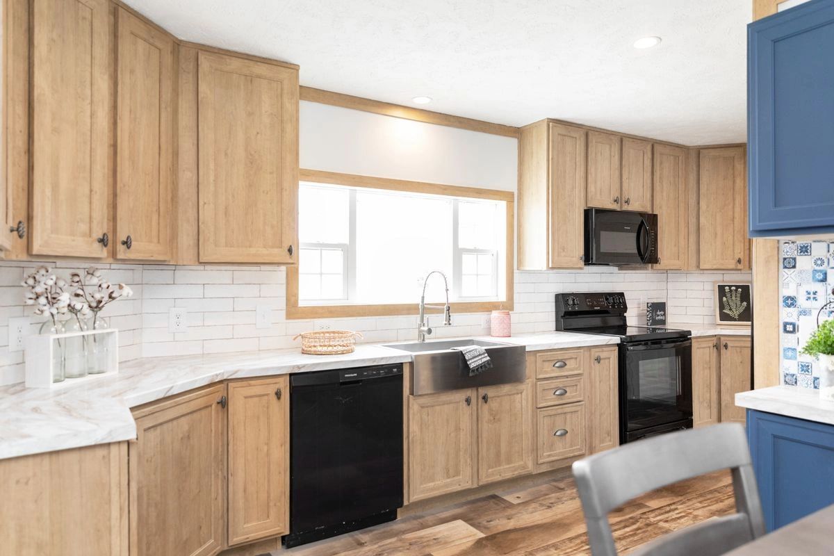 A kitchen with wooden cabinets , stainless steel appliances , a sink , and a window.