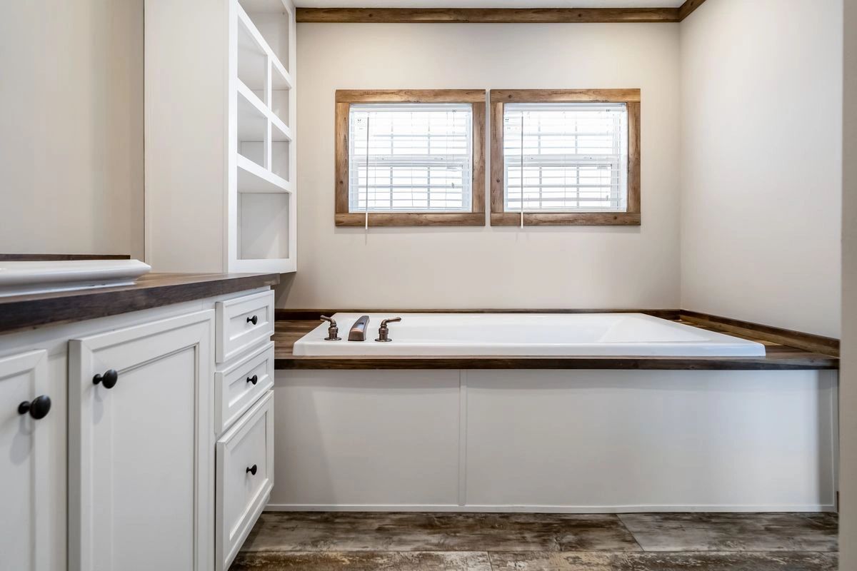 A bathroom with a large tub and two windows.