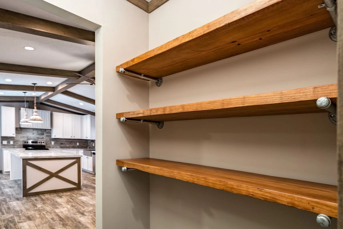 An empty pantry with wooden shelves in a kitchen.