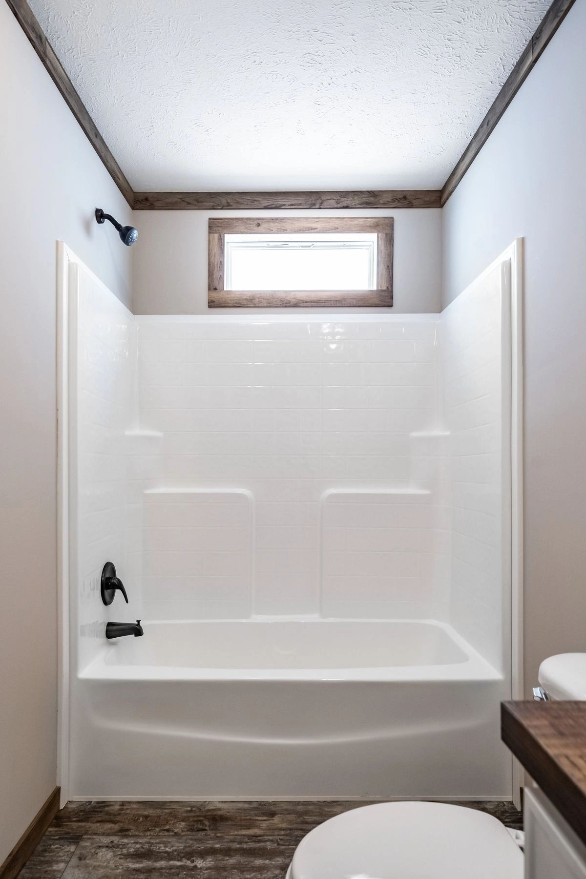 A bathroom with a tub , toilet , shower and window.