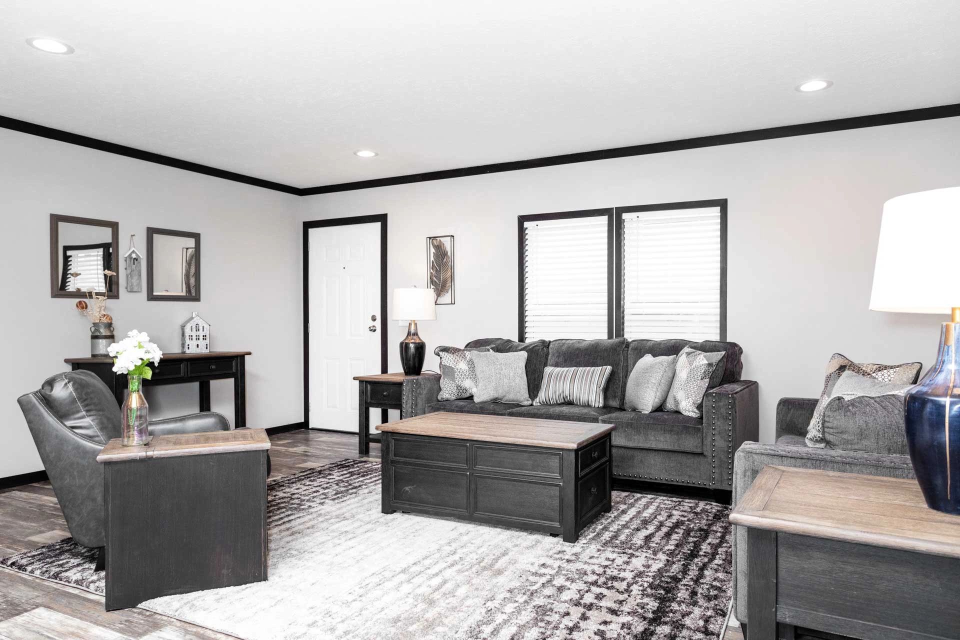 A living room with a couch , chairs , tables and a rug.