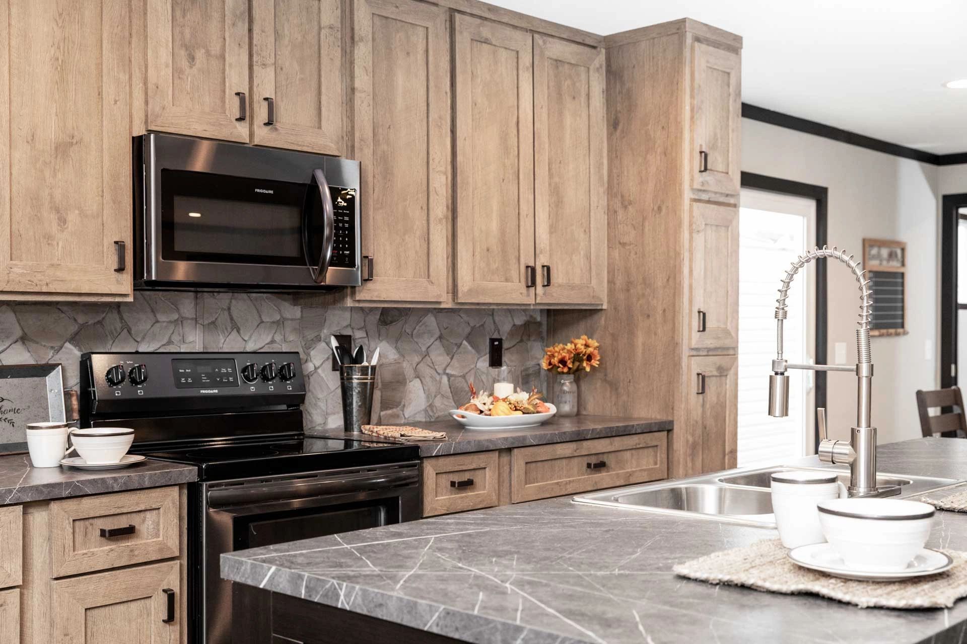 A kitchen with wooden cabinets , stainless steel appliances , a sink , and a microwave.