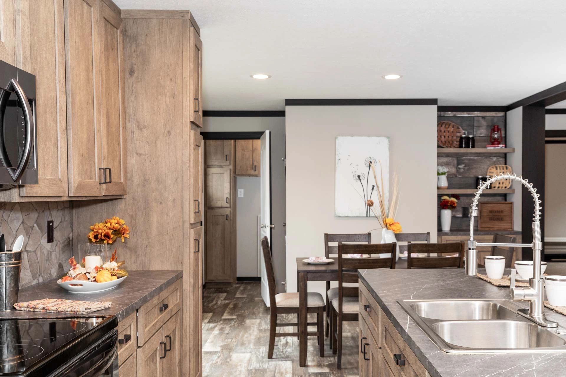 A kitchen with wooden cabinets , stainless steel appliances , a sink and a microwave.