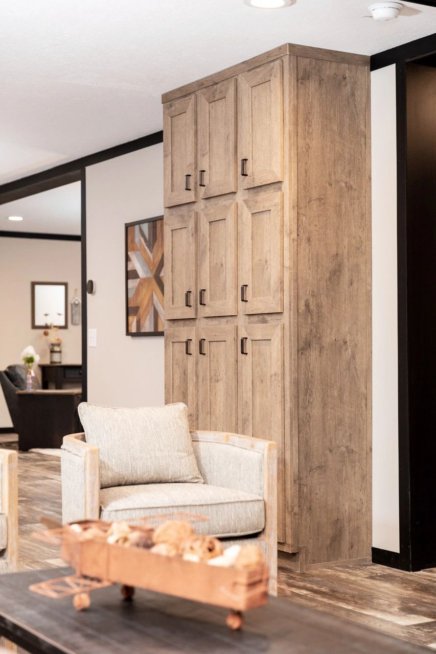 A living room with a chair , table and cabinets.