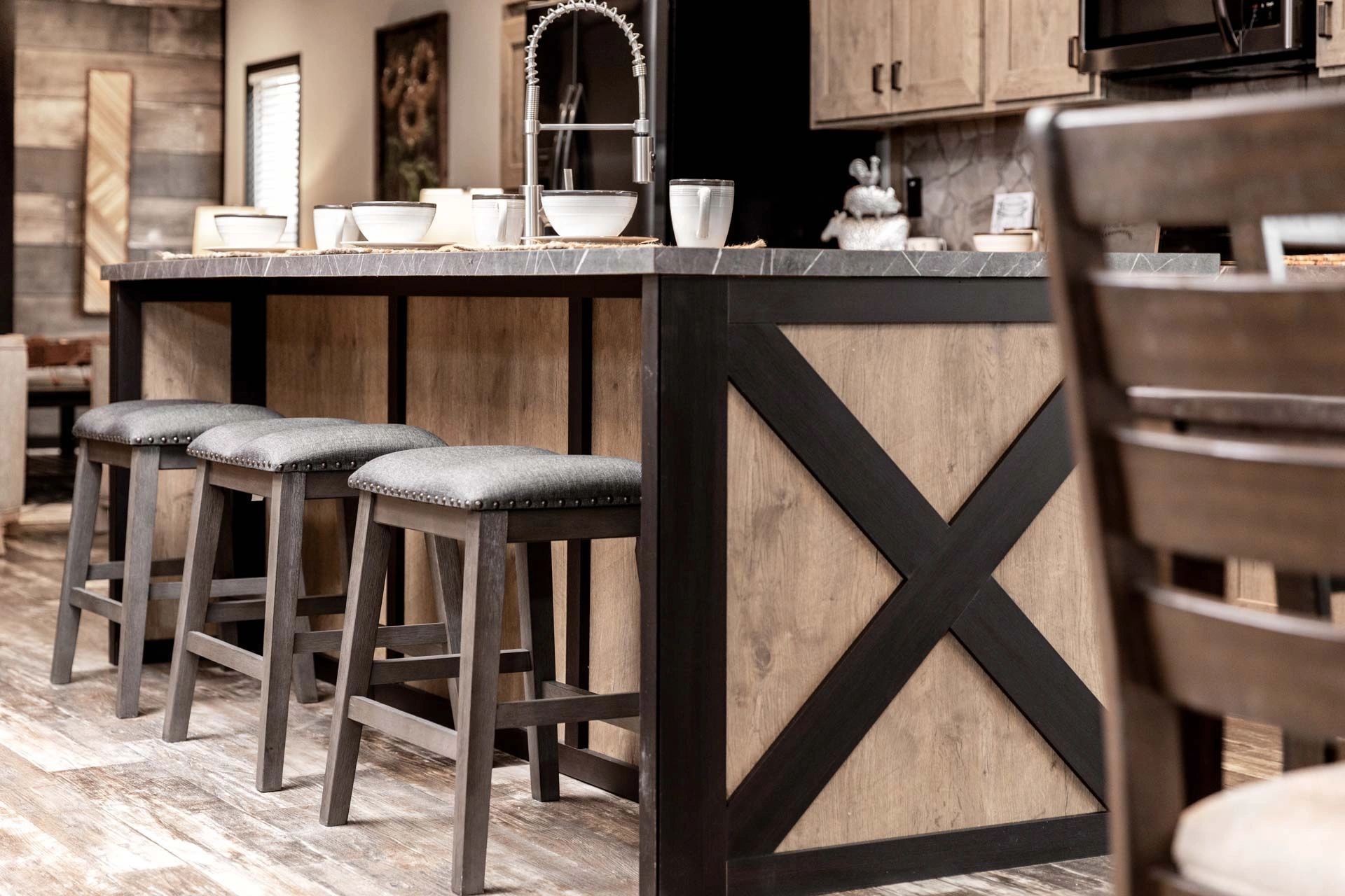 A kitchen with a large island and stools and a sink.