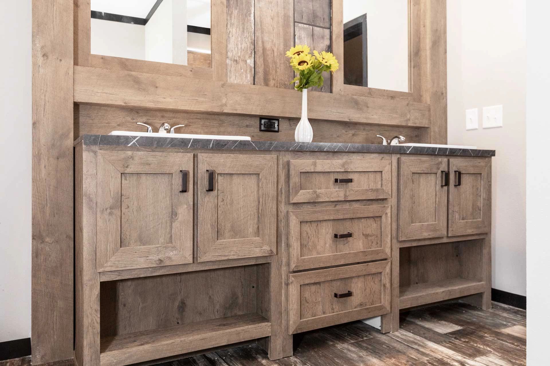 A bathroom with two sinks , a mirror , and wooden cabinets.