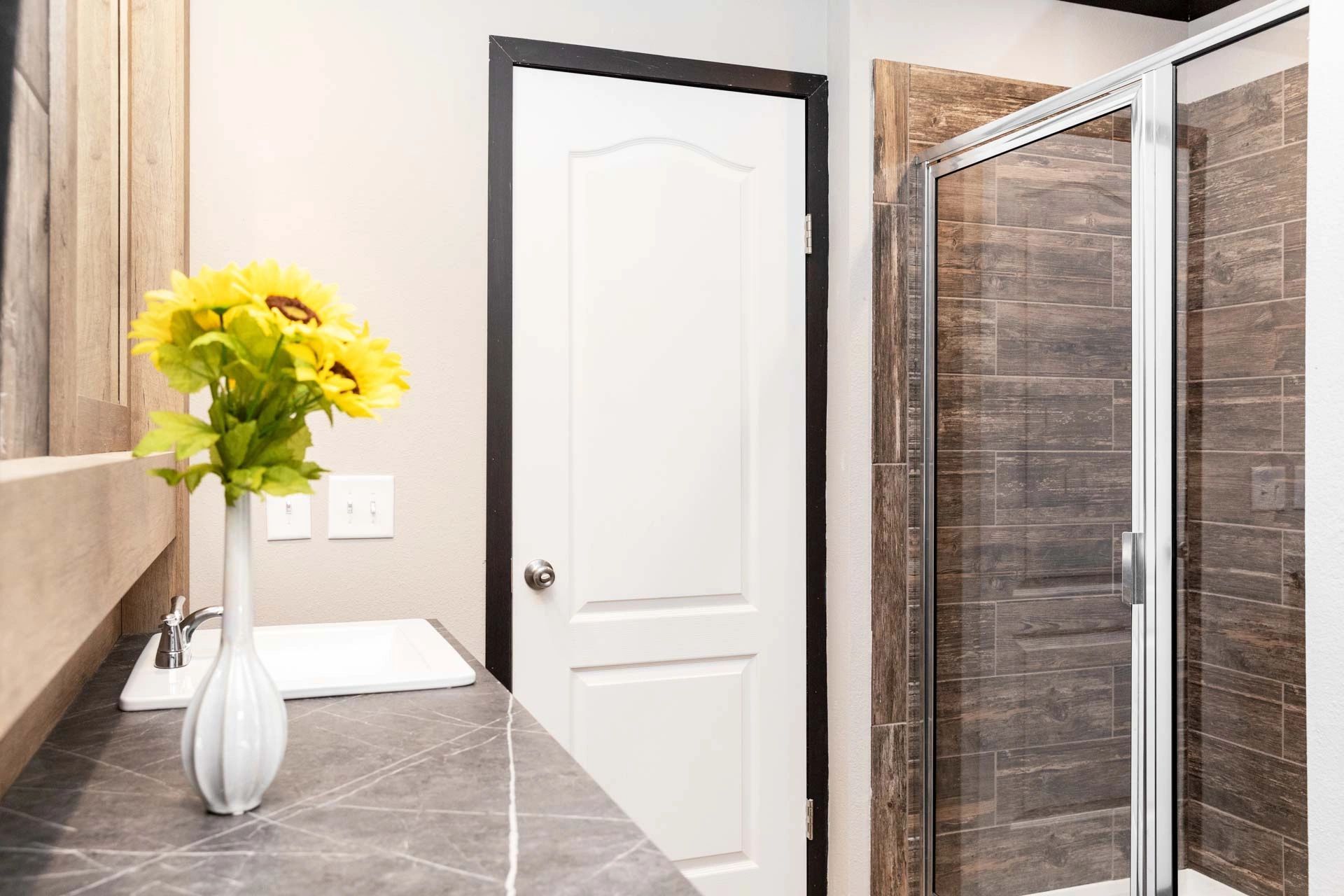 There is a vase of sunflowers on the counter in the bathroom.