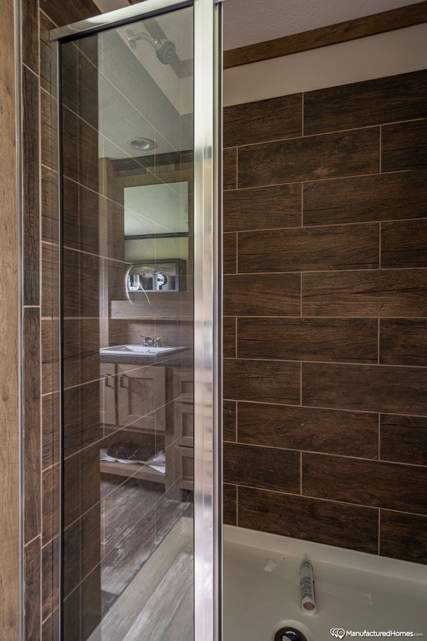 A bathroom with a tub , sink , mirror and shower stall.