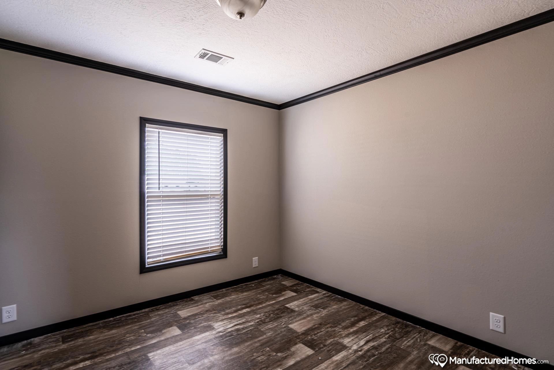 An empty bedroom with a window and blinds.
