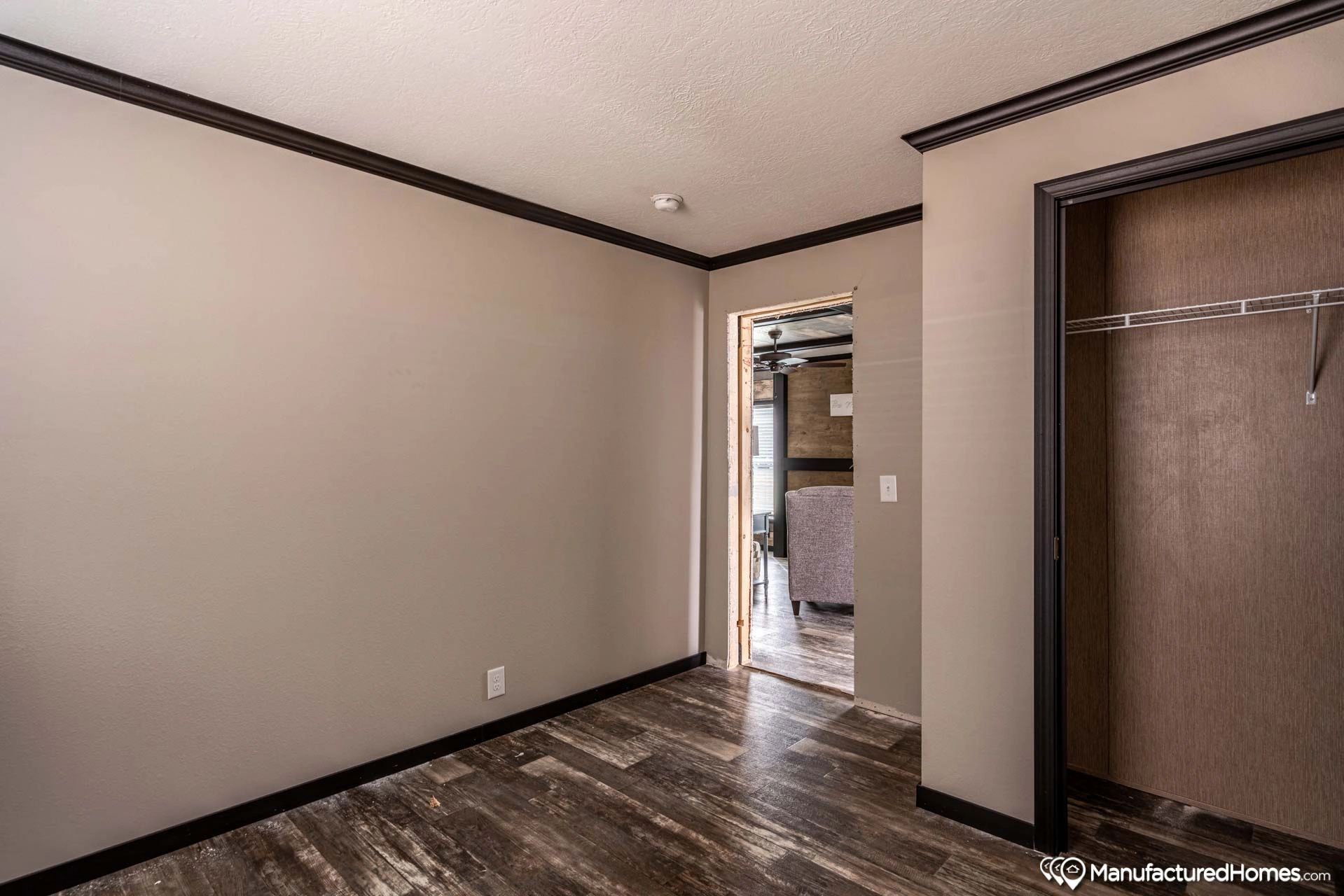 An empty room with a doorway leading to a living room and a closet.