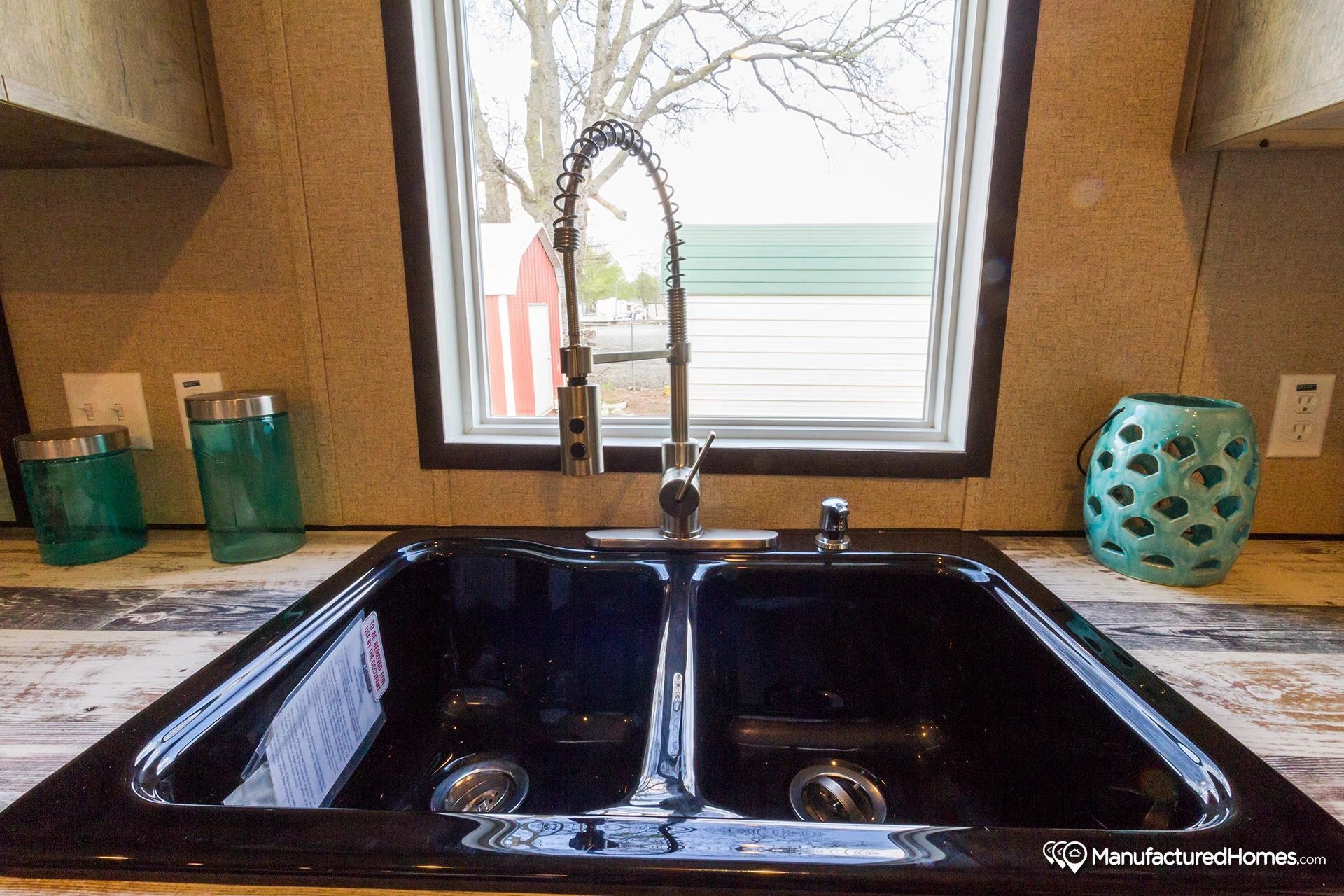 A kitchen sink with a faucet and a window in the background.