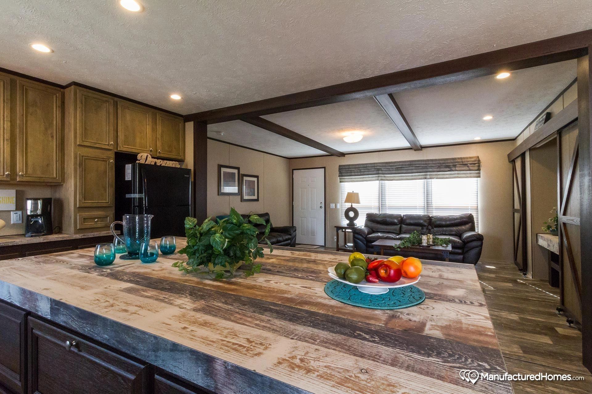 A kitchen with a large island and a bowl of fruit on it.