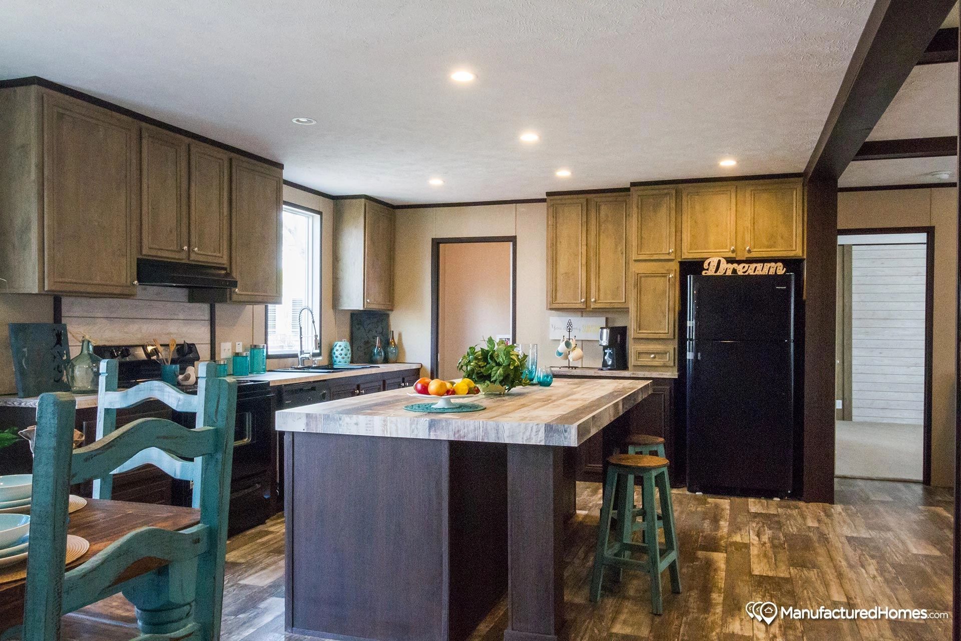 A kitchen with a large island and a black refrigerator.