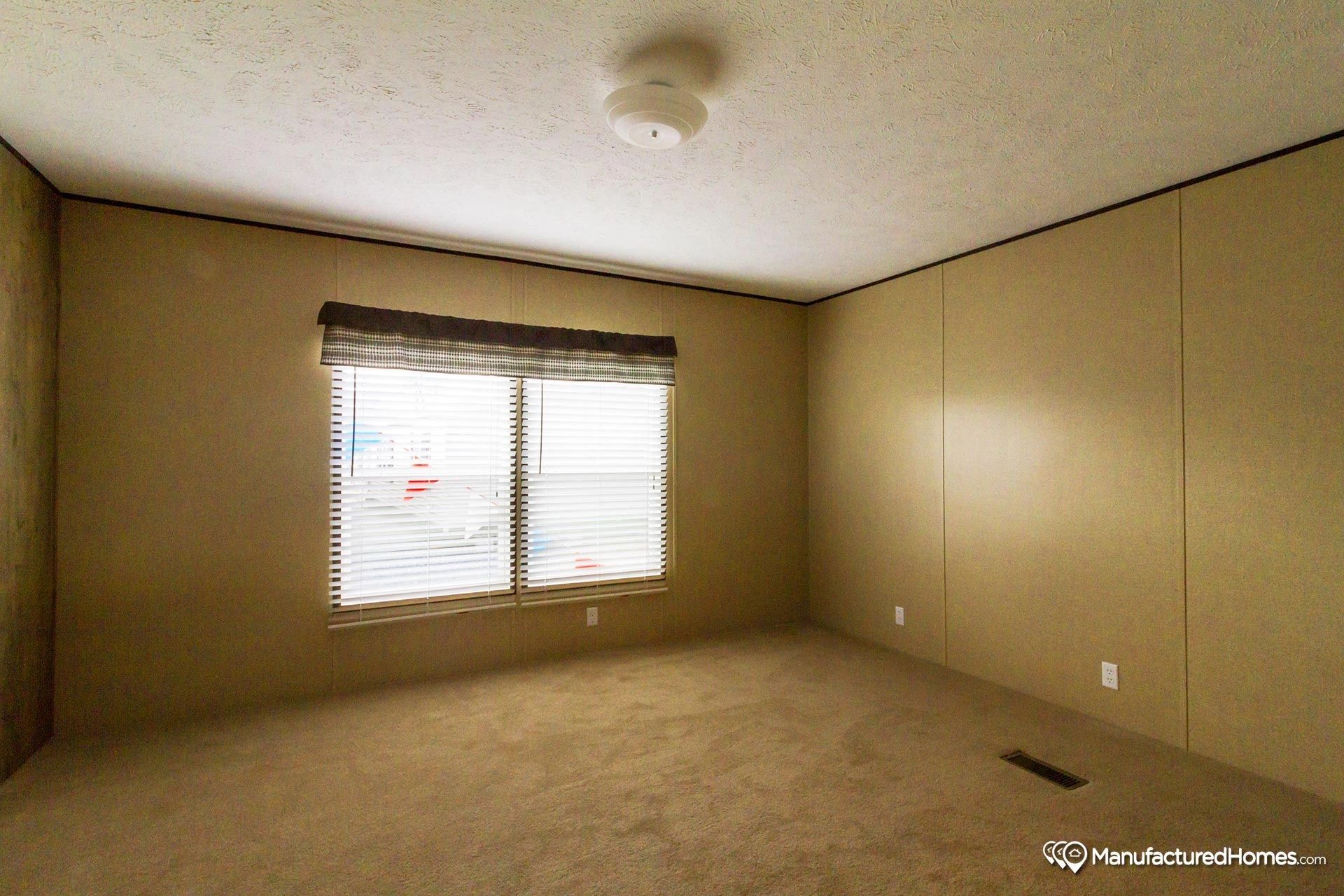 An empty room with two windows and a ceiling light