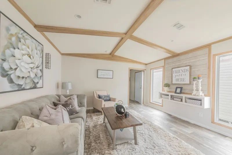 A living room with a couch , chair , coffee table and paintings on the wall.