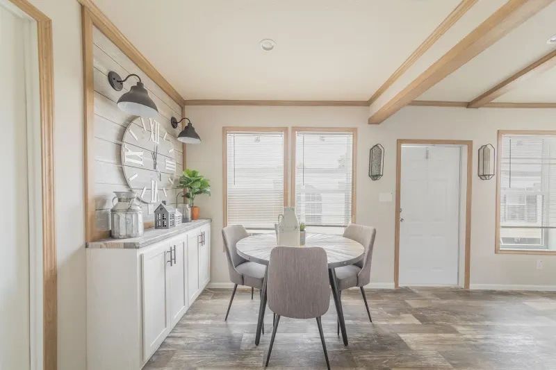 A dining room with a table and chairs and a clock on the wall.