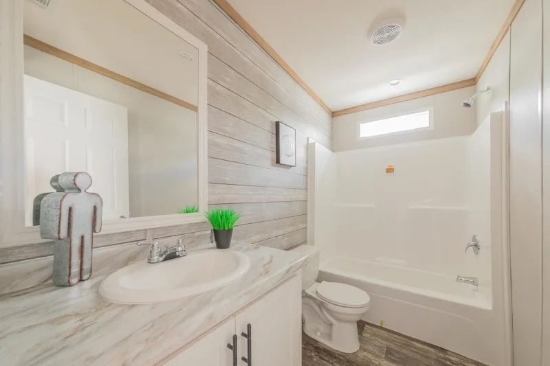 A bathroom with a sink , toilet , tub and mirror.