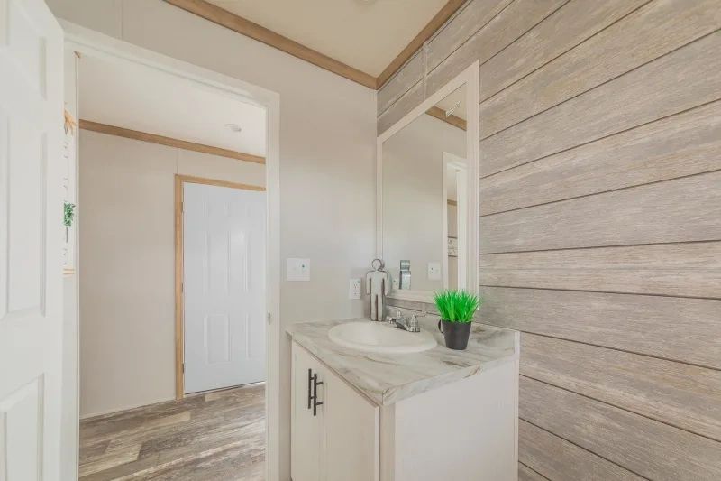 A bathroom with a sink , mirror and wooden wall.