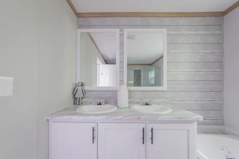 A bathroom with two sinks , two mirrors and a tub.