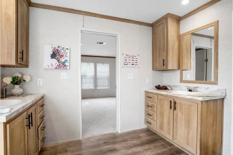 A bathroom in a mobile home with wooden cabinets and a sink.