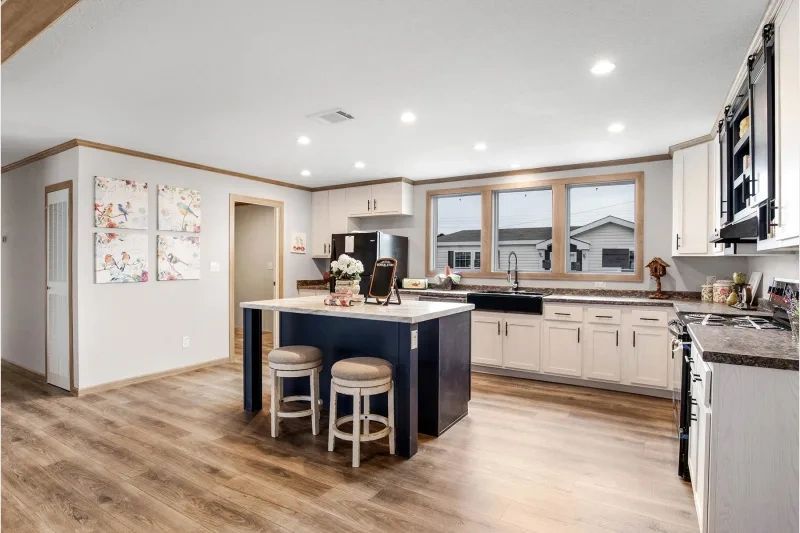 A kitchen in a mobile home with a large island and stools.