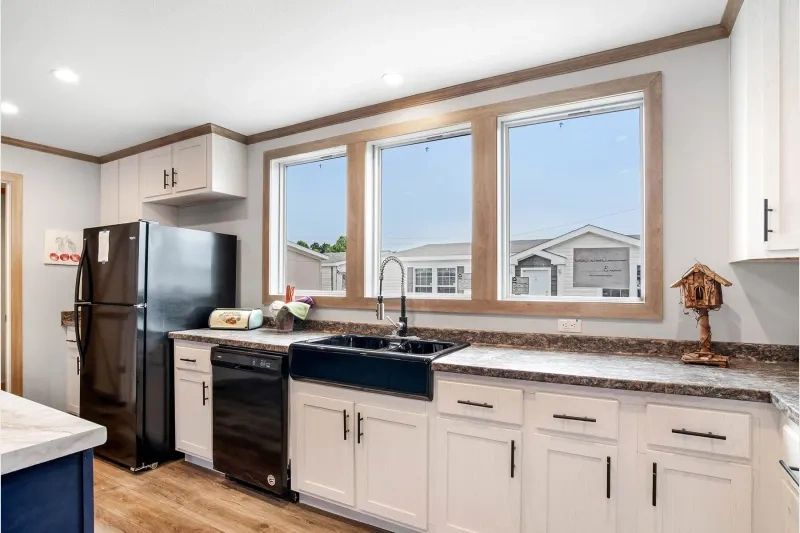 A kitchen with white cabinets , a refrigerator , a sink , and a dishwasher.