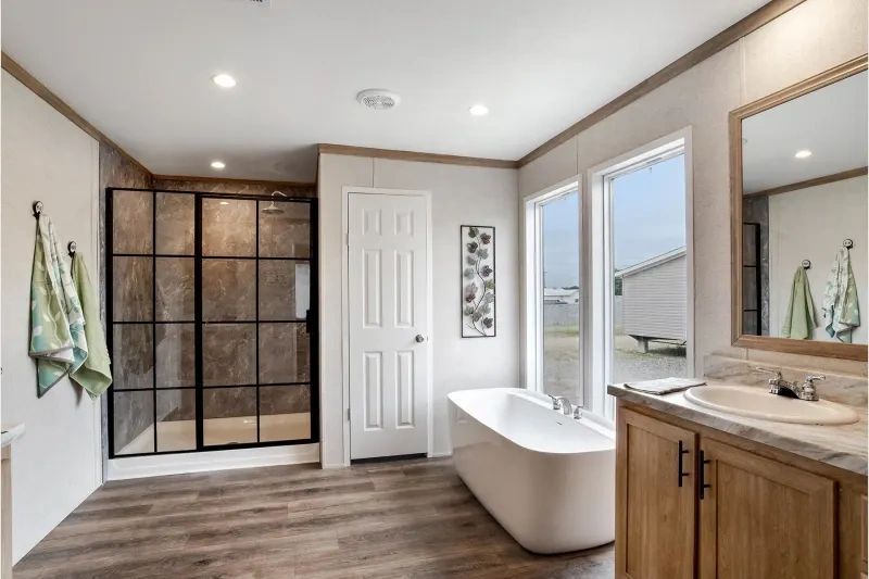 A bathroom with a tub , sink , mirror and shower.