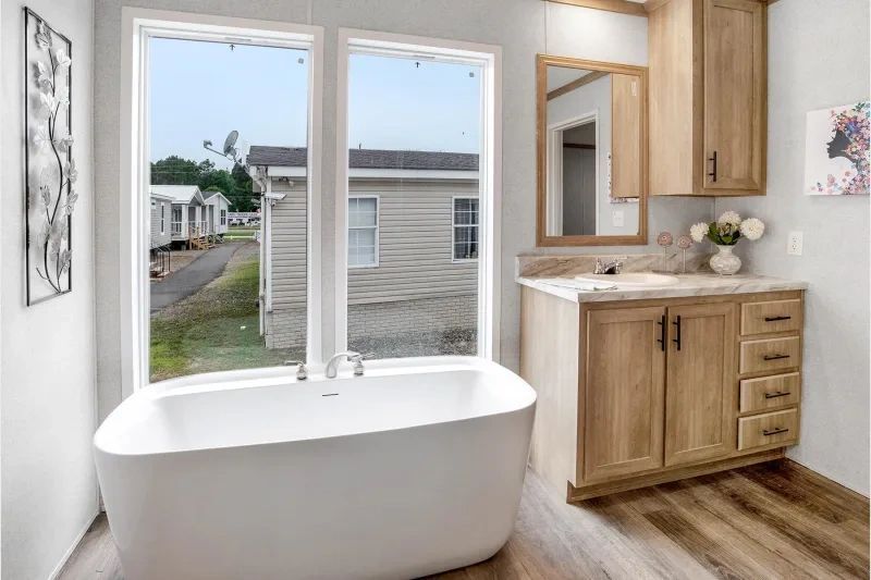 A bathroom with a tub , sink , mirror and cabinets.